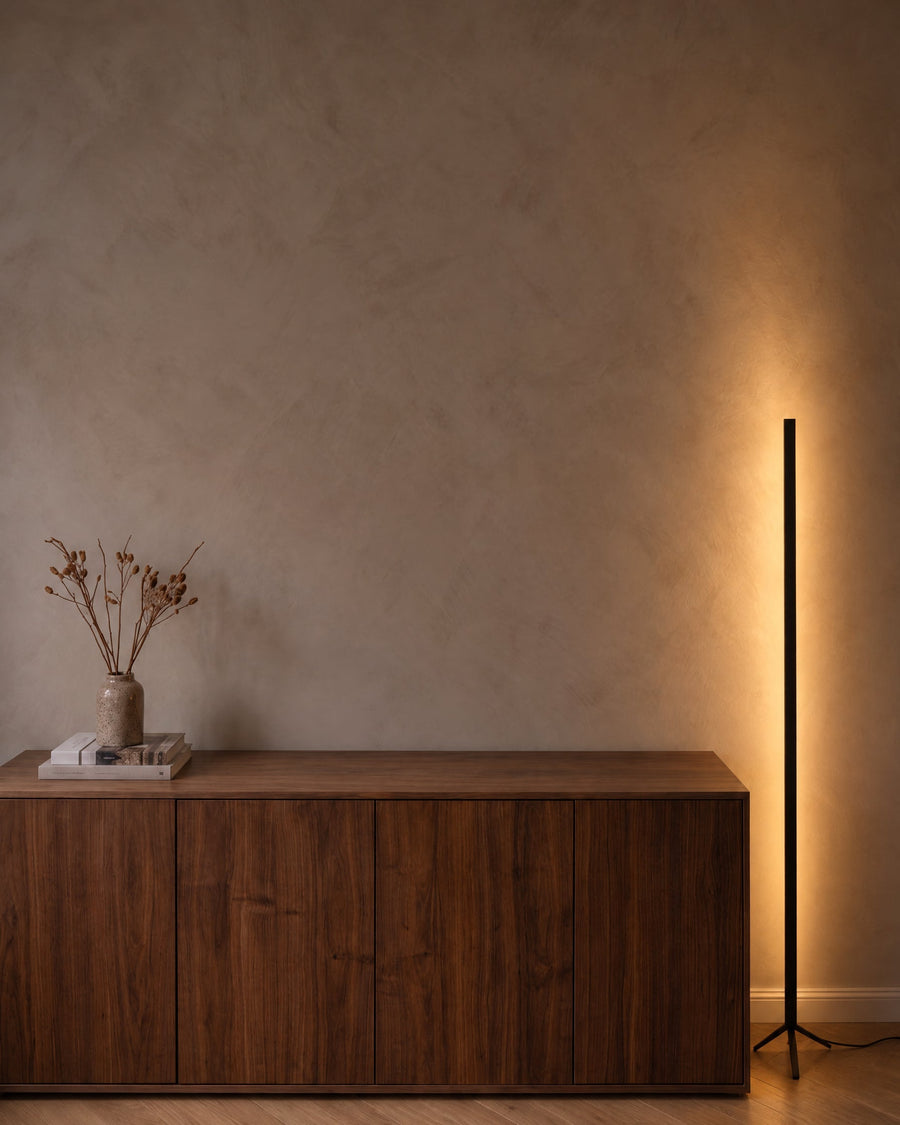 Black floor lamp with indirect light next to a sideboard