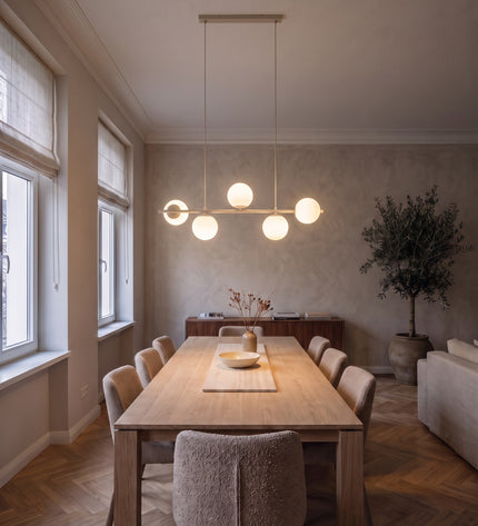 Cinque linear pendant light in beige with five opal glass globes above a dining table