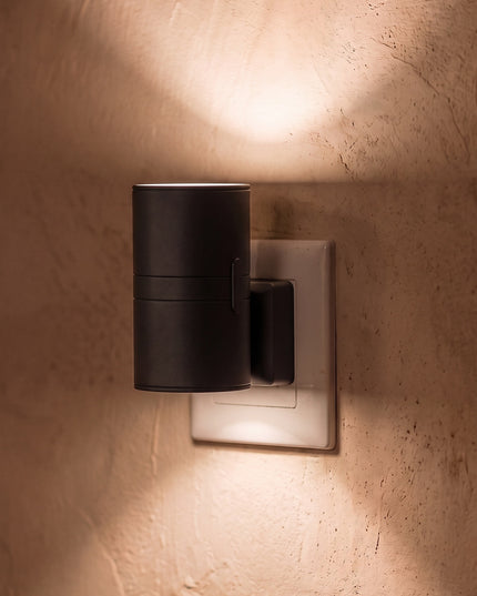 Nido plug-in wall light in black, plugged straight into a UK 3-pin socket, warm light up and down the wall