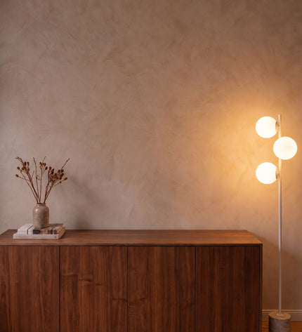 Perla floor lamp in white with three opal glass globes and stone base beside a walnut sideboard