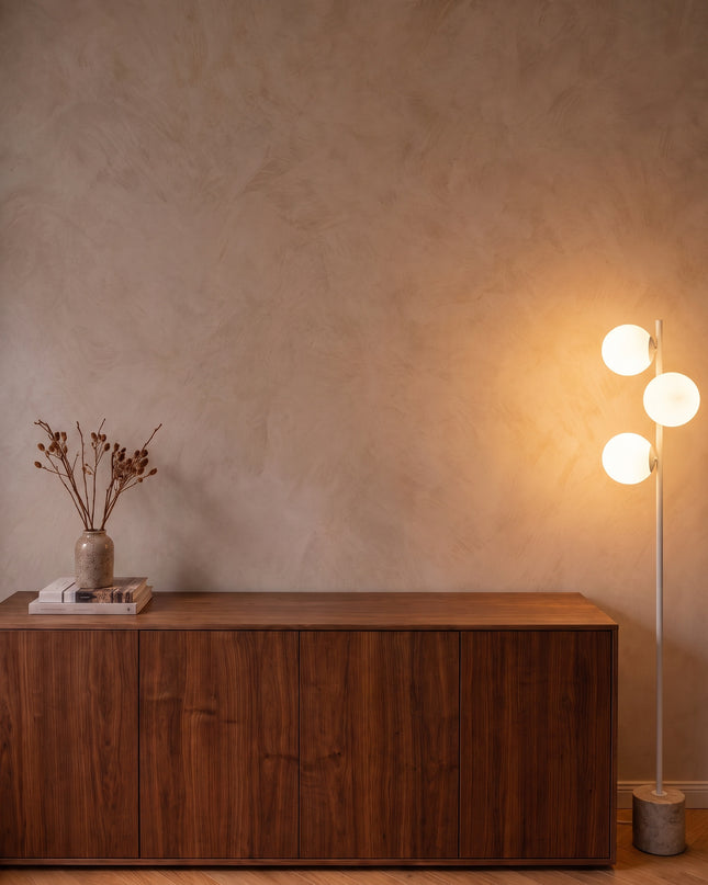 Perla floor lamp in white with three opal glass globes and stone base beside a walnut sideboard