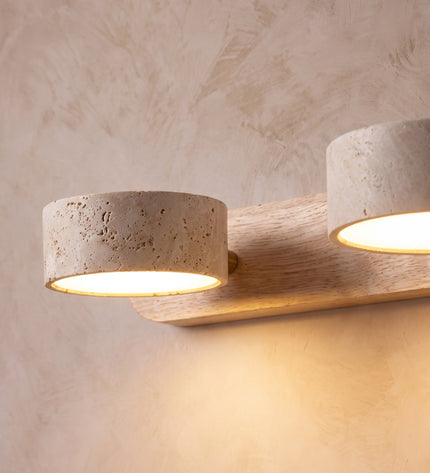 Cava wall light close-up: porous travertine shades on an oak backplate