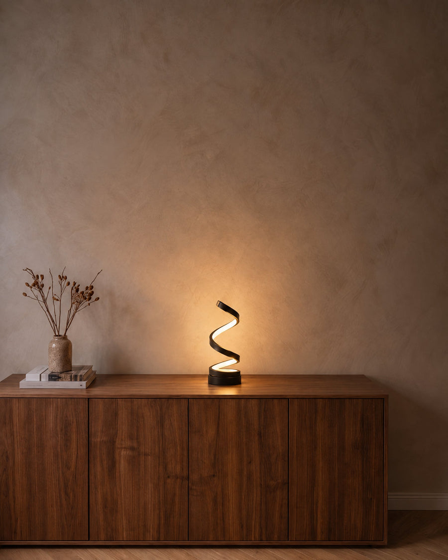 Spira spiral table lamp on a walnut sideboard in the evening