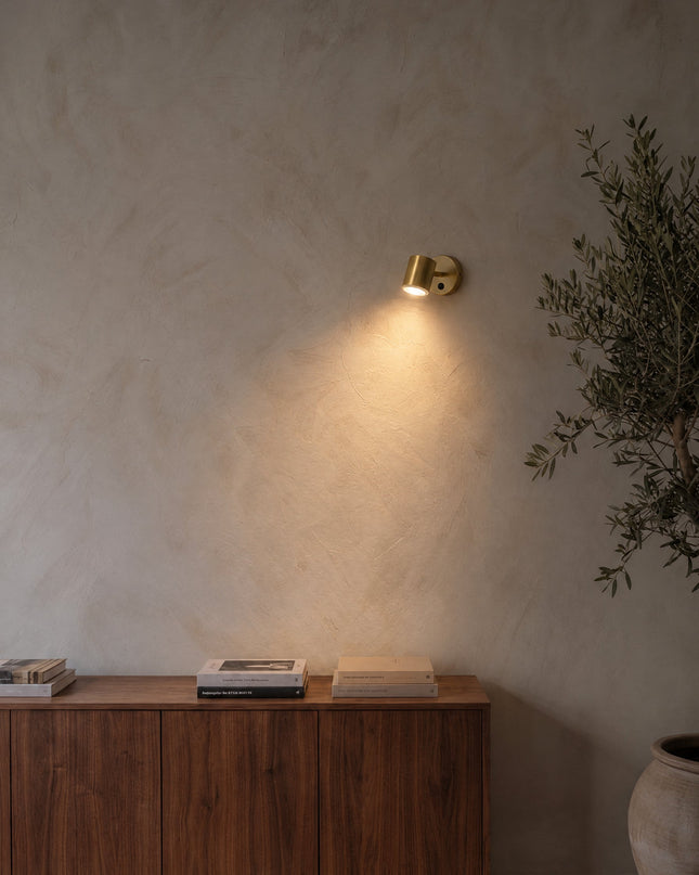 Varese Lampe Wandspot in Gold mit Zylinderkopf an einer Kalkputzwand