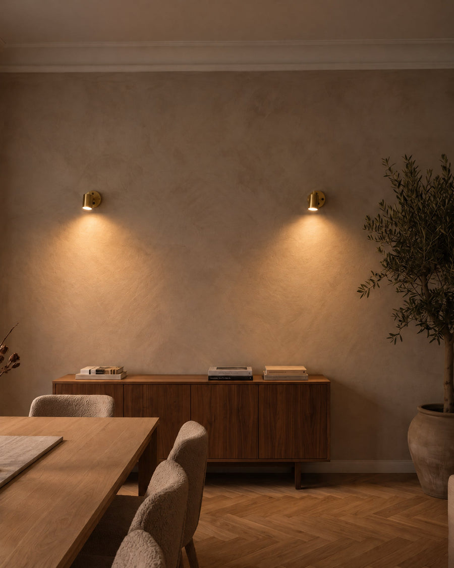 Two Varese wall spotlights in gold above a sideboard in a dining room