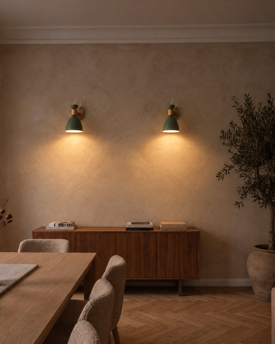 Two Berlin wall lamps in green above a walnut sideboard