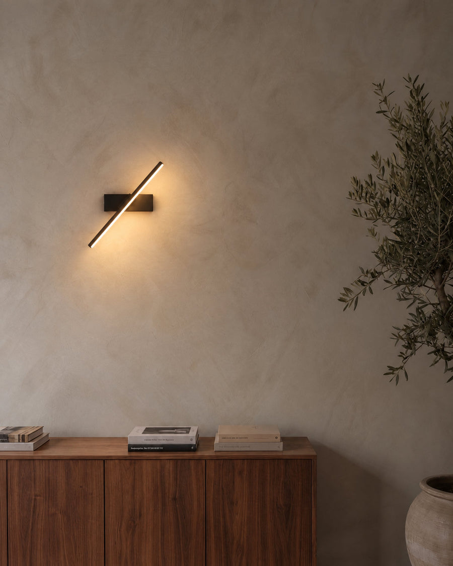 Rome LED wall light in black on a lime plaster wall