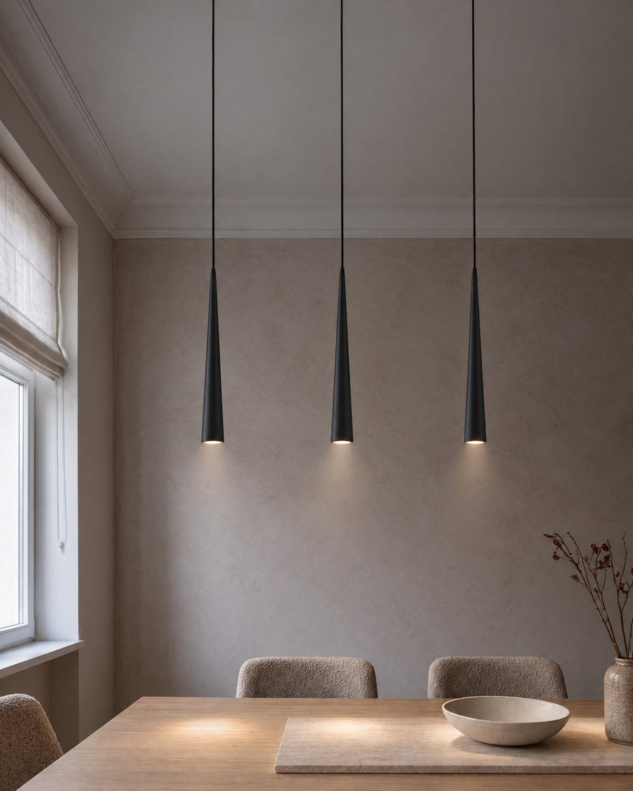 Three Lille pendant lights in black above an oak dining table