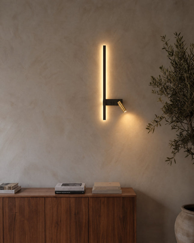 Norda Wandleuchte Modell C in Schwarz mit goldenem Leselicht an einer Kalkputzwand
