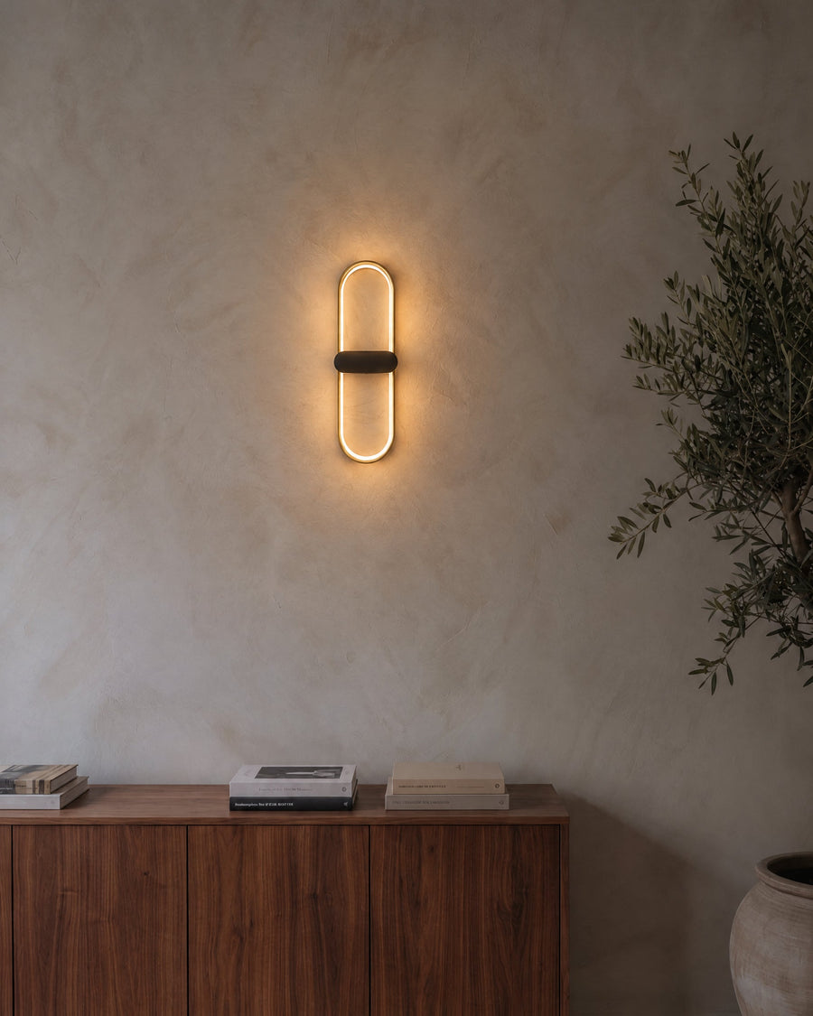 Lunaris wall light in gold and black on a lime plaster wall