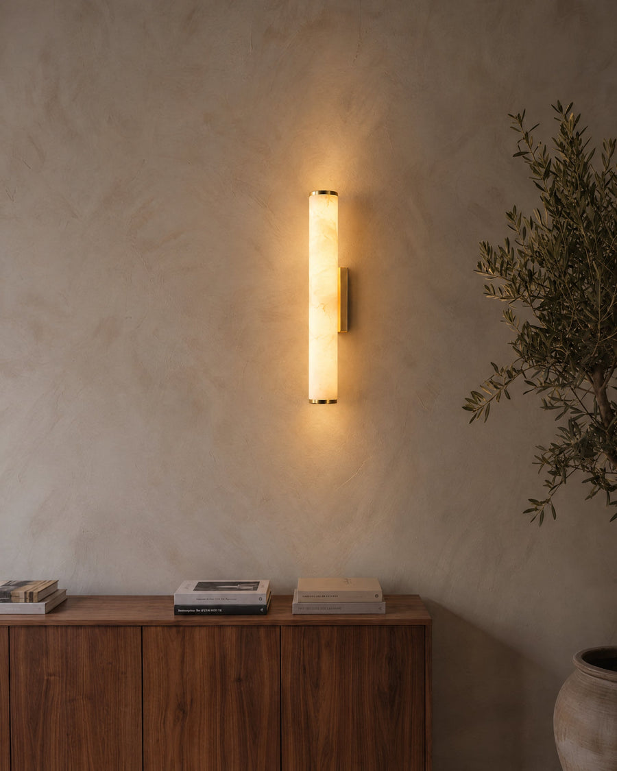 Klyr wall light in brass and white on a lime plaster wall