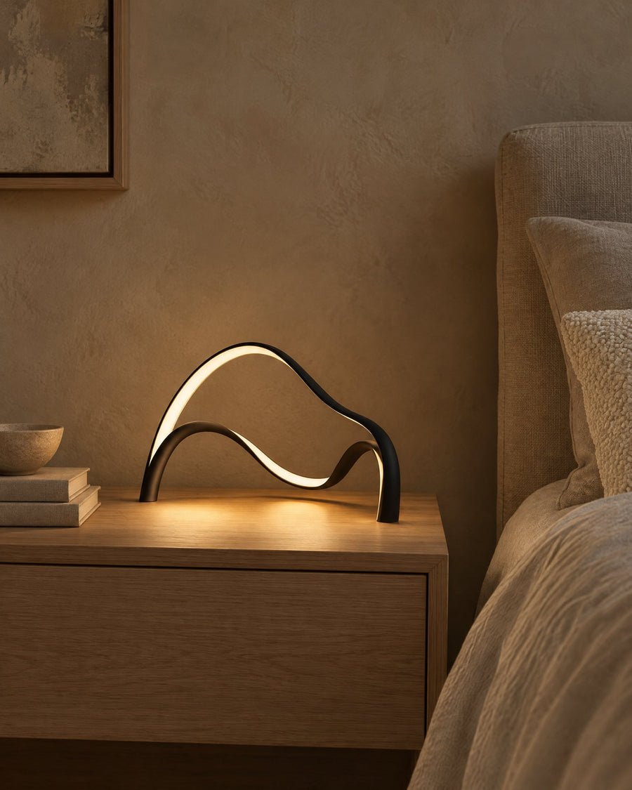 Volta table lamp glowing on an oak bedside table in the bedroom