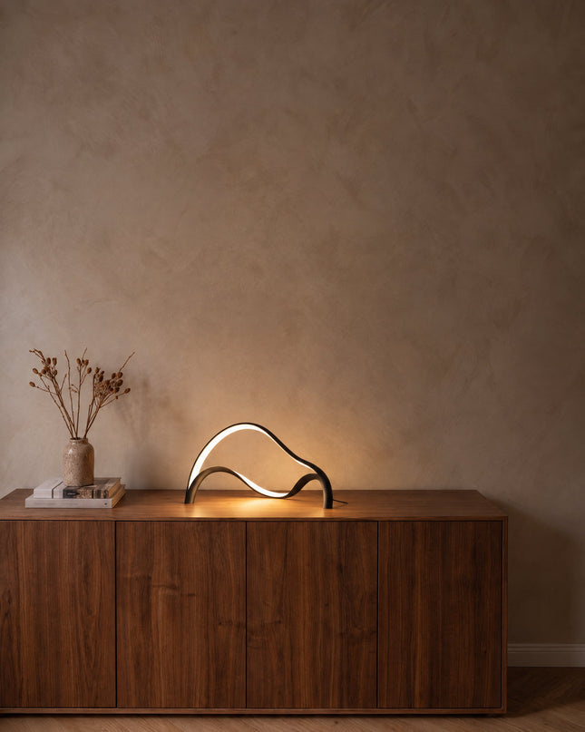 Volta sculptural LED table lamp in matt black on a walnut sideboard