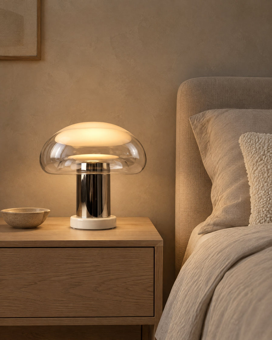 Nebbia table lamp glowing on an oak bedside table in the bedroom