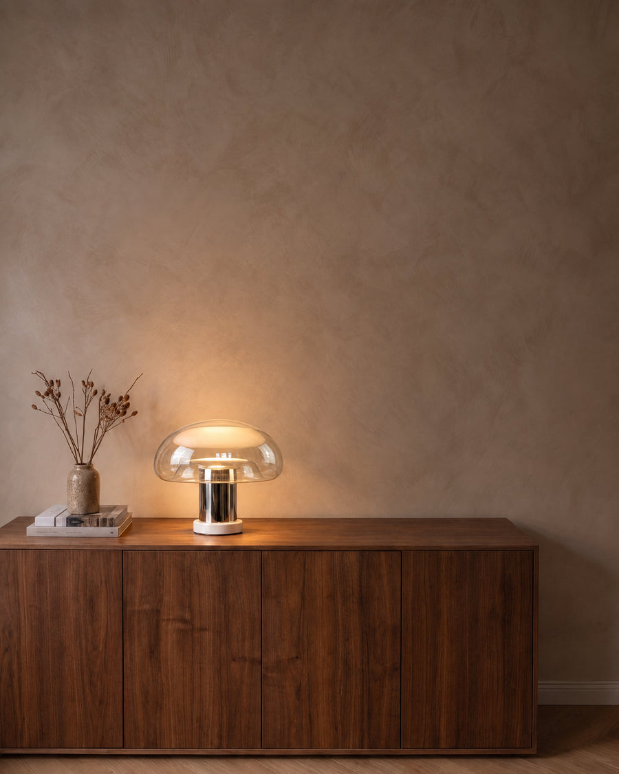 Nebbia glass mushroom table lamp with chrome stem on a walnut sideboard