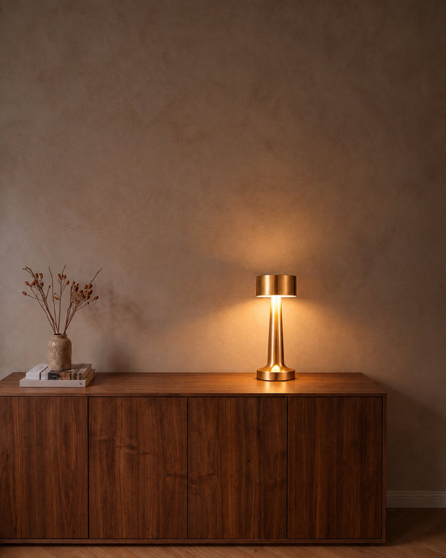 Tondo cordless table lamp in gold, switched on, on a walnut sideboard