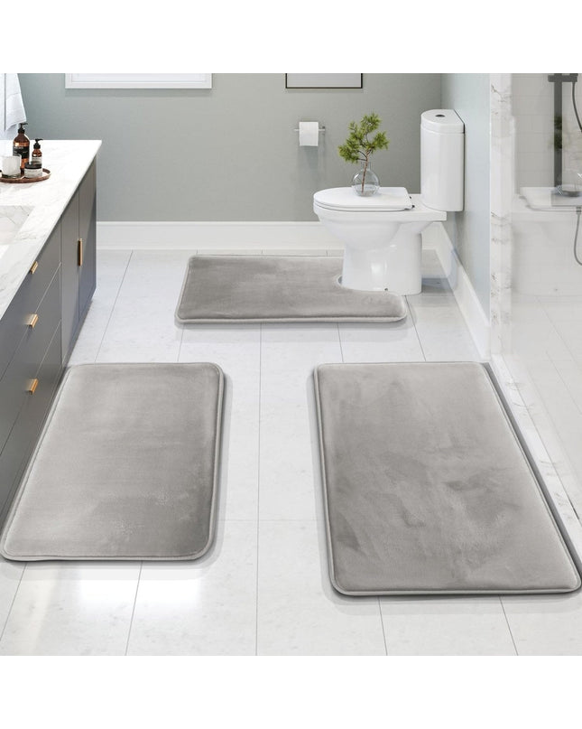 Kezaro Rivano 3-piece beige bath mat set with textured fabric, including a large bath rug and two smaller matching mats.