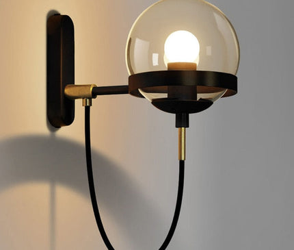 Black Strasbourg wall light by Kezaro with a sleek, modern design and cylindrical shape, mounted on a white wall.