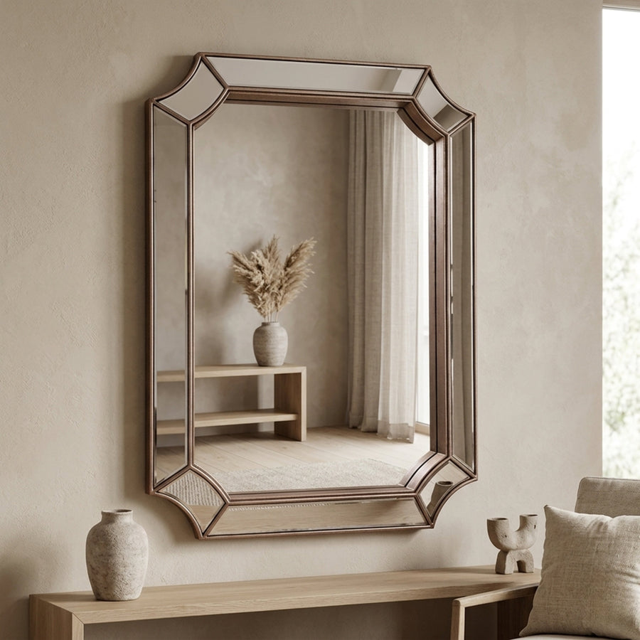 Mira wall mirror with faceted frame in silver above a console table