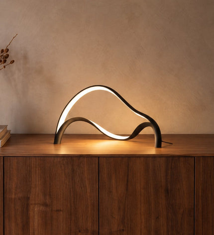 Volta sculptural LED table lamp in matt black on a walnut sideboard