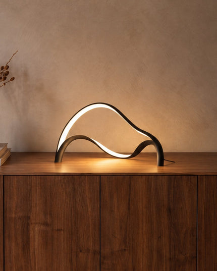 Volta sculptural LED table lamp in matt black on a walnut sideboard