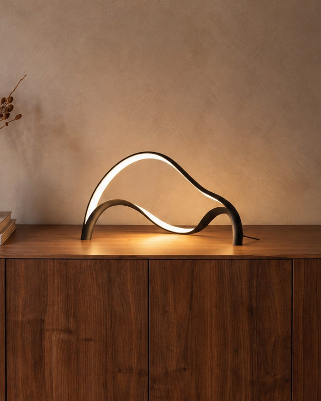 Volta sculptural LED table lamp in matt black on a walnut sideboard